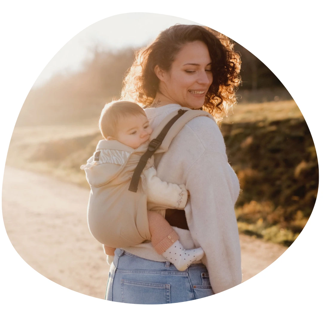 Porte bébé en voyage : photo d'une maman en randonnée, avec son bébé de 6 mois installée en porte-bébé dans son dos.