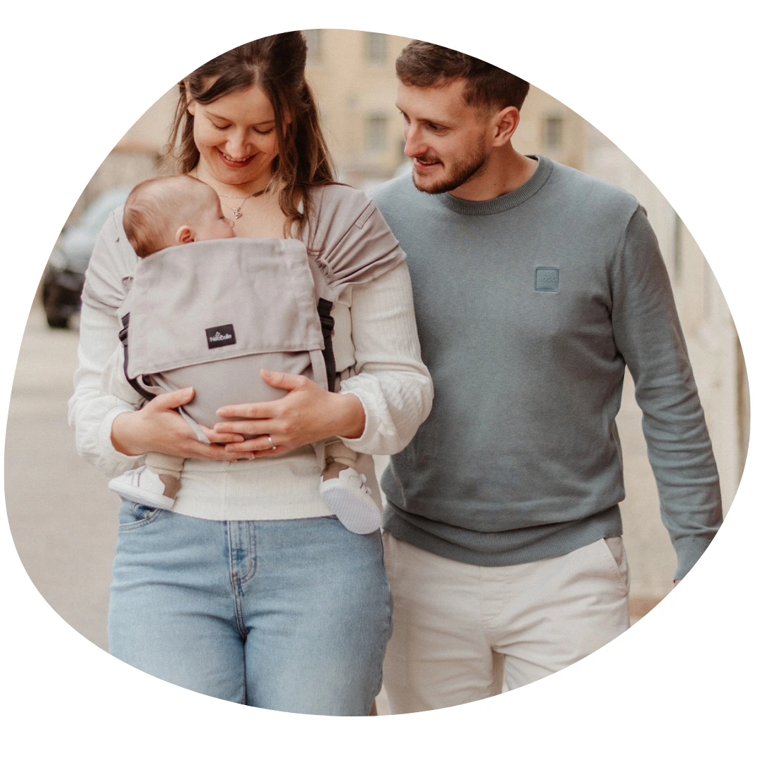 Porte bébé en voyage : photo de deux parents en balade dans une ville, avec leur bébé installé en Pti-Evo de Néobulle.
