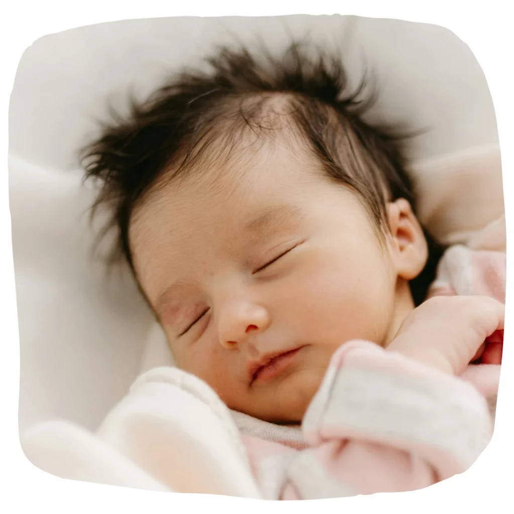 Poux chez bébé : c'est possible : Photo d'un bébé endormi, avec une chevelure bien fournie.
