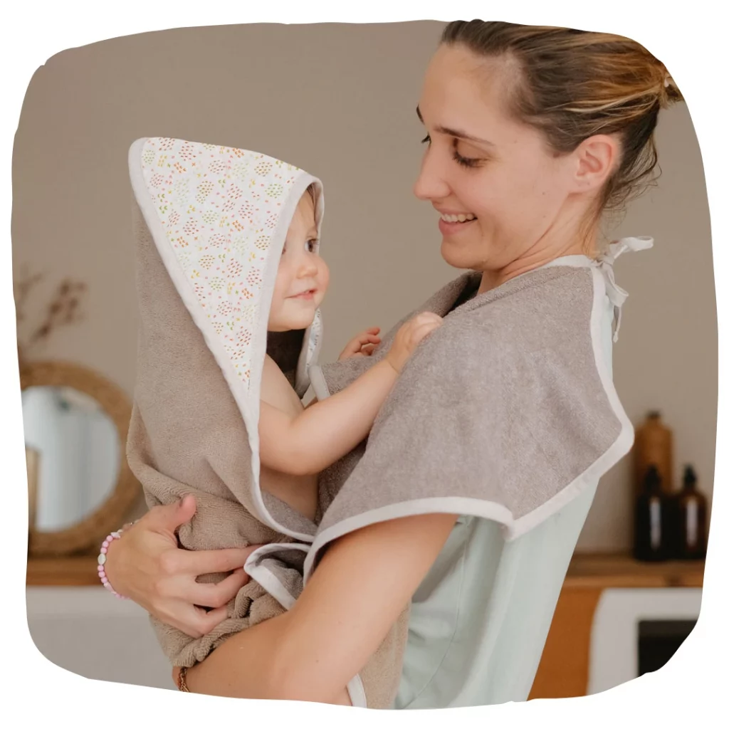 Poux chez bébé : photo d'une maman avec son bébé en serviette de bain, qui vient d'être traité contre les poux.