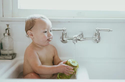Comment se débarrasser des poux chez bébé, nos conseils ! Photo d'un bébé de 6 mois dans sa baignoire.