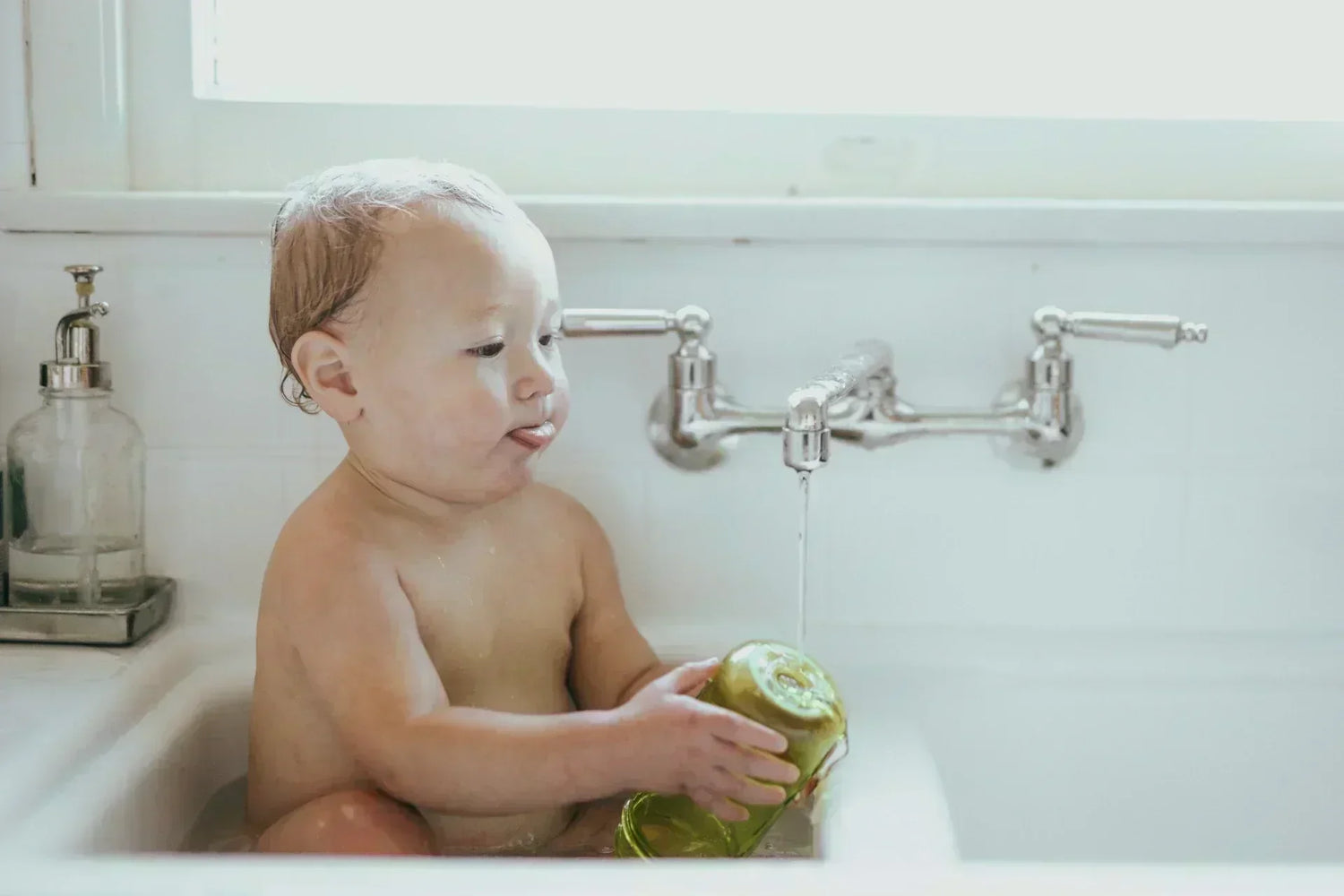 Comment se débarrasser des poux chez bébé, nos conseils ! Photo d'un bébé de 6 mois dans sa baignoire.